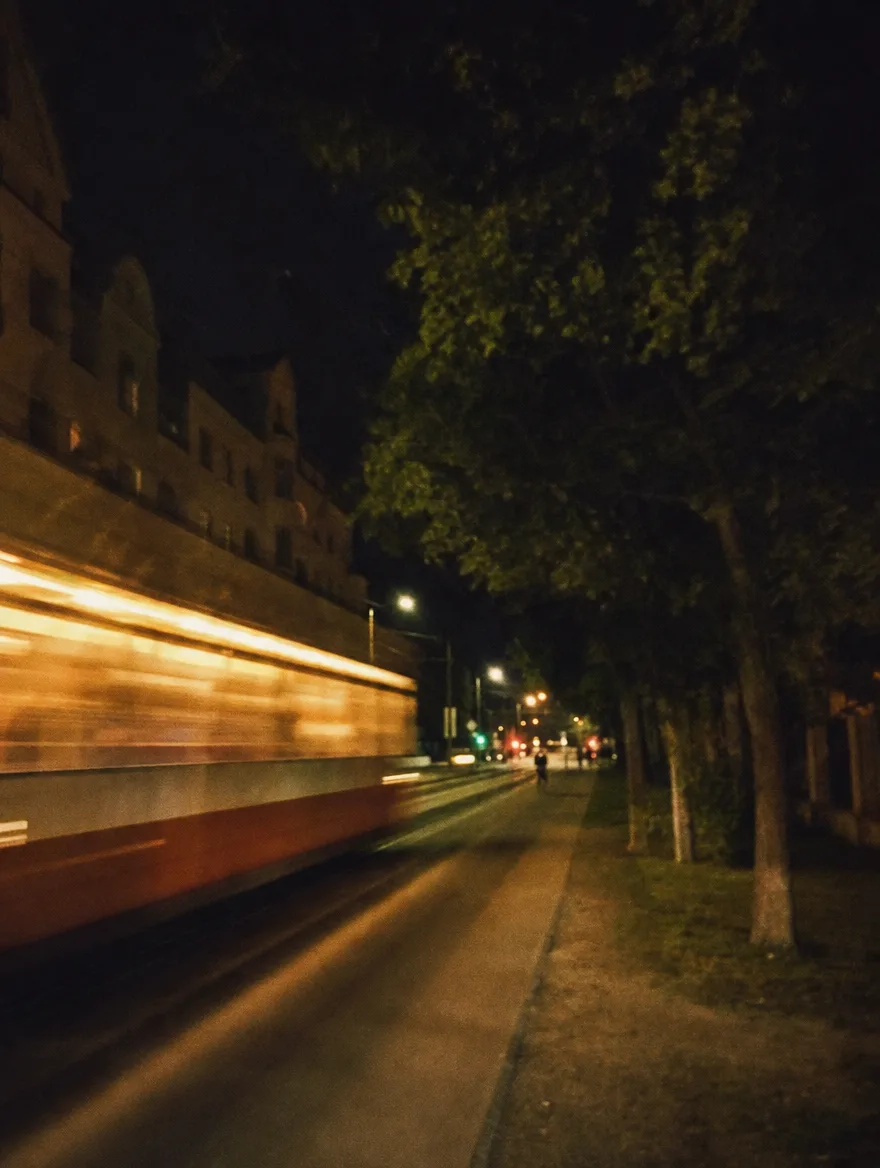 Tramwaj jako pozioma smuga światła na letniej ulicy.